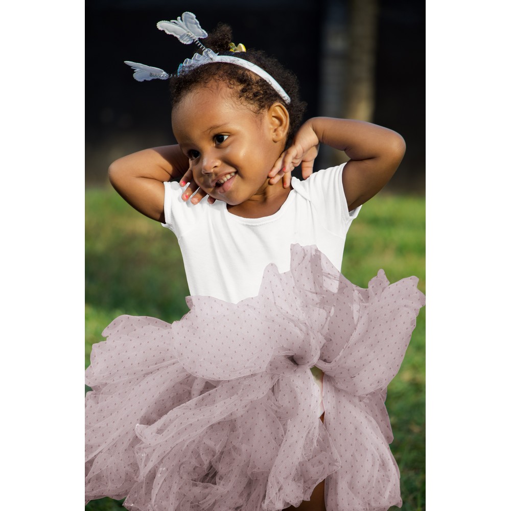 Naeratav tüdruk roosas tüllseelikus õues mängimas