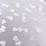 Hõbedased südamekujulised sädelused hallil kangal