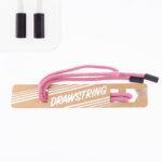 Roosa nöörmustade otstega pakendil sildiga.