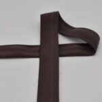 Tumepruun elastne lint valgel taustal