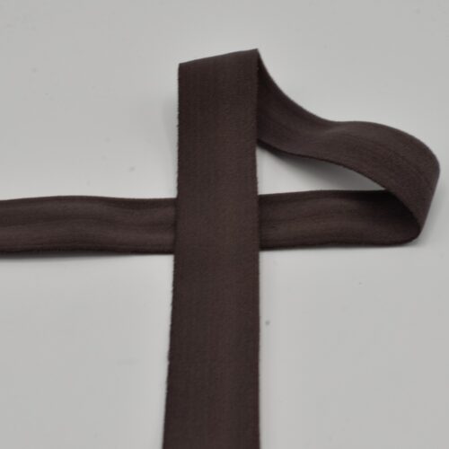 Tumepruun elastne lint valgel taustal