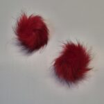 Kaks punast karvast pom-pomi valgel taustal