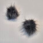 Kaks halli karvast pompooni valgel taustal