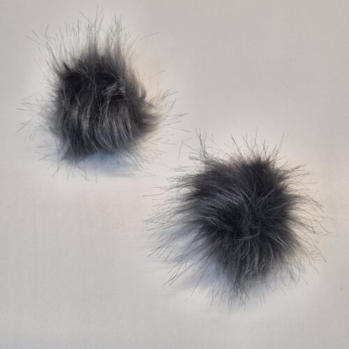 Kaks halli karvast pompooni valgel taustal