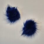 Kaks sinist karvast pom-pomi valgel taustal