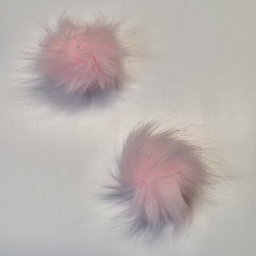 Kaks roosat karvast pom-pomi valgel taustal