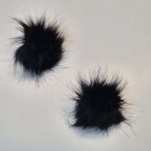 Kaks musta karvast pompooni valgel taustal