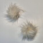 Kaks valget karvast pom-pom palli valgel taustal