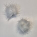 Kaks valget kunstkarvast pom-pomi valgel taustal