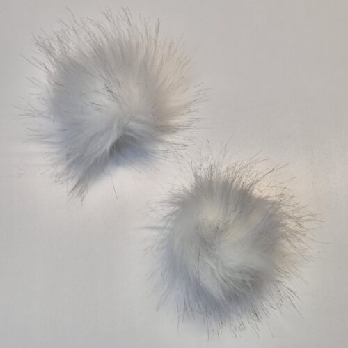 Kaks valget kunstkarvast pom-pomi valgel taustal