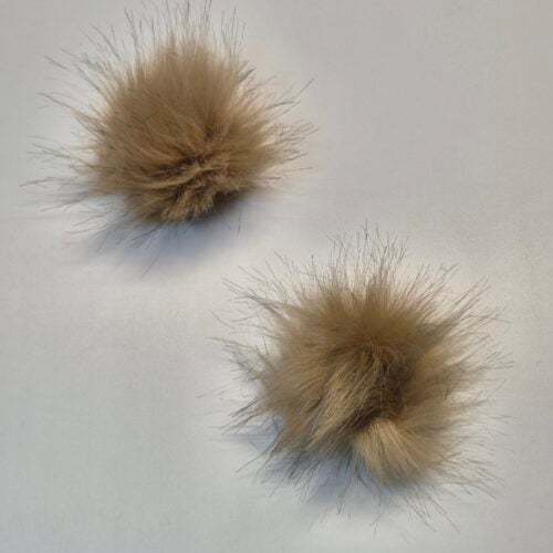 Kaks pruuni karvast pompommi valgel taustal