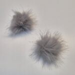 Kaks halli karvast pom-pomi tasasel pinnal