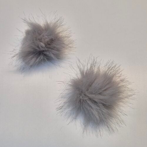 Kaks halli karvast pom-pomi tasasel pinnal