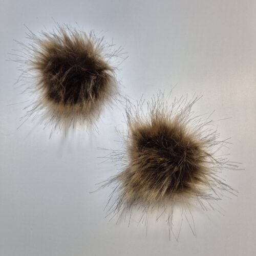 Kaks pruuni karvast pom-pomi valgel taustal