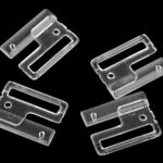 Neli läbipaistvat plastklambrit mustal taustal