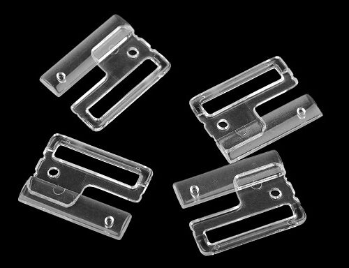 Neli läbipaistvat plastklambrit mustal taustal