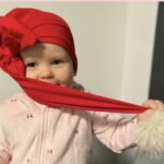 Beebi punase mütsiga mängib salli otsaga.