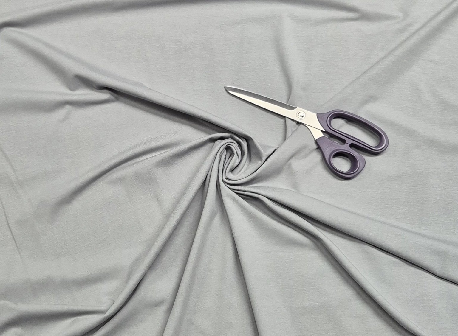 Purple scissors on twisted gray fabric