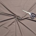 Scissors on twisted brown fabric background