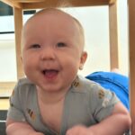 Iloinen vauva lattialla pöydän alla